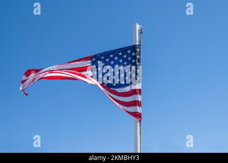 Amerikanische Sterne und Stiefflaggen wehen im Wind vor dem Hintergrund eines blauen Himmels Stockfoto