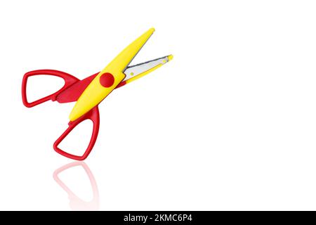 Rot-gelbe offene Kunststoffschere isoliert auf weißem Hintergrund, mit Reflexion. Stockfoto