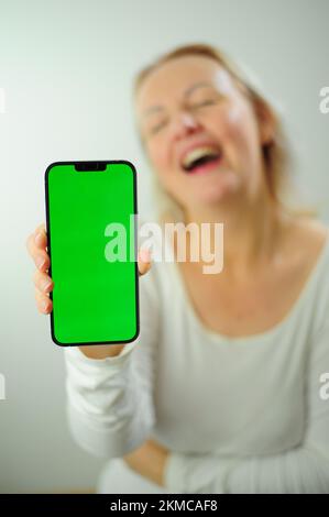 Gewinnen, um zu finden, was Freude Freude Freude Freude Freude Freude andere Emotionen Chroma Key Phone Grünes Bildschirmfeld für Werbung schöne Erwachsene glückliche Frau Stockfoto