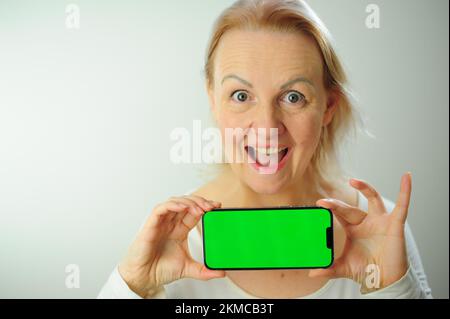 Gewinnen, um zu finden, was Freude Freude Freude Freude Freude Freude andere Emotionen Chroma Key Phone Grünes Bildschirmfeld für Werbung schöne Erwachsene glückliche Frau Stockfoto