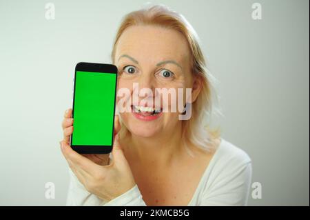 Gewinnen, um zu finden, was Freude Freude Freude Freude Freude Freude andere Emotionen Chroma Key Phone Grünes Bildschirmfeld für Werbung schöne Erwachsene glückliche Frau Stockfoto