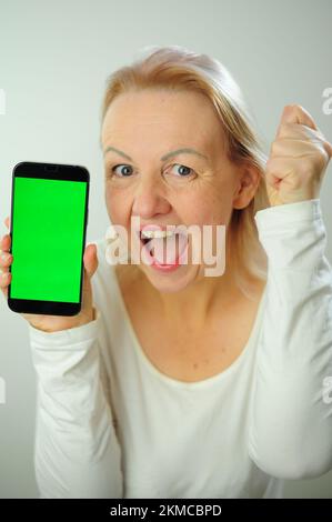 Gewinnen, um zu finden, was Freude Freude Freude Freude Freude Freude andere Emotionen Chroma Key Phone Grünes Bildschirmfeld für Werbung schöne Erwachsene glückliche Frau Stockfoto