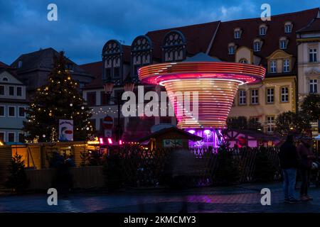 Naumburg, Deutschland. 26.. November 2022. Auf dem Weihnachtsmarkt in Naumburg gibt es ein Karussell (lange Exposition) neben einer beleuchteten Tanne. Neben dem Weihnachtsmarkt haben zahlreiche Institutionen sowie Unternehmen und Privatpersonen ihre Höfe am ersten Adventswochenende in Naumburg eröffnet. Besucher können Bereiche sehen, die ansonsten nicht sichtbar sind. Kredit: Frank Hammerschmidt/dpa/Alamy Live News Stockfoto