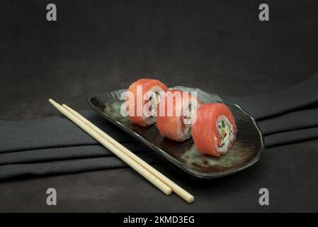 Foto von köstlichem Sushi auf dunklem Hintergrund Stockfoto