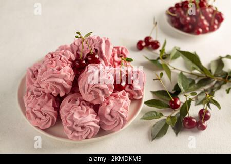 Köstliche süße zephyr und Kirschen auf hellem Hintergrund, das Konzept einer gesunden und gesunden Eigenproduktion. Stockfoto