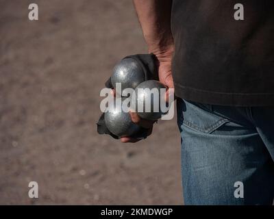 Ein Mann, der bereit ist, den Boules-Ball auf einem Platz zu werfen, im Freien Boccia spielen, Petanque Stockfoto