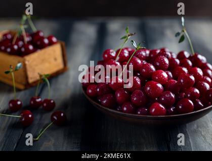 Reife Kirschen auf einem Teller auf einem Holztisch, leckere, süße Beere aus Naturprodukten ohne Pestizide, rustikaler Stil Stockfoto