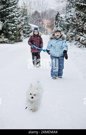 Lustige Spiele, die Kinder im Schnee spielen können. Winteraktivitäten im Freien für Kinder und Familie. Glückliche Kinder, die Spaß haben, laufen, zusammen Schneeball spielen Stockfoto