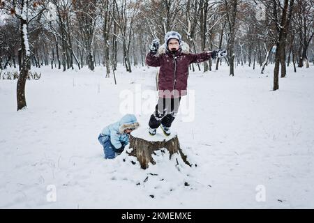 Lustige Spiele, die Kinder im Schnee spielen können. Winteraktivitäten im Freien für Kinder und Familie. Glückliche Kinder, die Spaß haben, laufen, zusammen Schneeball spielen Stockfoto