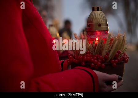 Kiew, Ukraine. 26.. November 2022. Eine ukrainische Frau hält eine Laterne an der Statue „Bitter Memory of Childhood“, die den Opfern der Holodomor-Hungersnot an einem verschneiten Abend in den Pechersk Hills am 26. November 2022 in Kiew, Ukraine, gewidmet ist. Die Ukraine feiert den 90.. Jahrestag des Massenhunger der Ukrainer durch Stalin, der 4 Millionen Menschen tötete. Kredit: Ukrainischer Ratsvorsitz/Pressestelle Des Ukrainischen Präsidenten/Alamy Live News Stockfoto