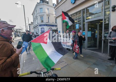 London, Großbritannien. 26. November 2022. Hackney Palestine Solidarity Campaign Nehmen Sie an einem nationalen Aktionstag Teil und fordern einen Boykott der Barclays Bank wegen ihrer Investitionen in den israelischen Waffenhersteller Elbit und andere Unternehmen, die die illegale Besetzung palästinensischen Landes unterstützen. Sie verteilen Flugblätter vor der Bank in Dalston und informieren die Menschen über die Unterstützung der Bank für das israelische Apartheid-Regime. Ähnliche Maßnahmen wurden auch in anderen Bankfilialen in London und im gesamten Vereinigten Königreich durchgeführt. Peter Marshall/Alamy Live New Stockfoto