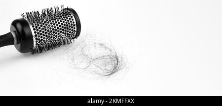 Haarverlustproblem der Frau mit einer runden Haarbürste auf weißem Hintergrund. Weißer Hintergrund. Haare fallen, Haarbürste mit Haaren Stockfoto