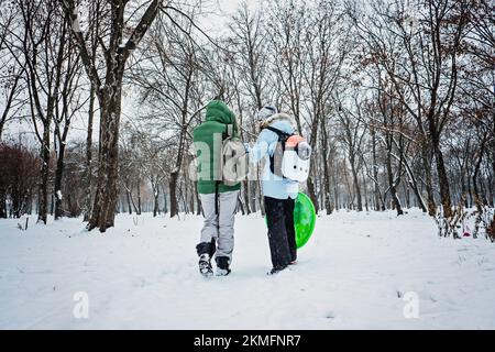 Winteraktivitäten im Freien für Familie und Freunde. Fröhliche Familie, Freunde, zwei Frauen, zwei Jungen und Hunde, Mütter und Söhne, die spazieren gehen und Spaß im Freien haben Stockfoto