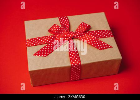 Abonnementboxen für Übergabe und Empfang. Geschenkbox für Abonnement, Care-Paket mit rotem Band auf rotem Hintergrund. Stockfoto