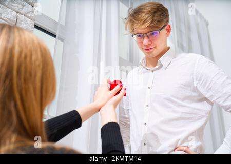 Peinlicher Moment. Junge Frau hält Box mit Verlobungsring und macht Heiratsantrag an ihren Freund. Stockfoto