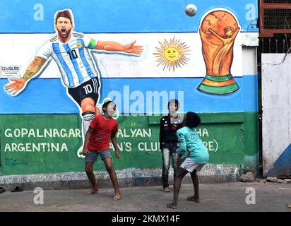 Kalkutta, Indien. 26.. November 2022. Während der FIFA-Weltmeisterschaft 2022 in Kalkutta spielen Kinder vor der Mauer des argentinischen Fußballers Lionel Messi auf einer Straße. (Foto: Sudipta das/Pacific Press) Kredit: Pacific Press Media Production Corp./Alamy Live News Stockfoto