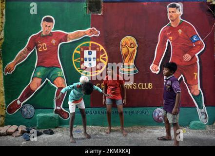 Kalkutta, Westbengalen, Indien. 26.. November 2022. Kinder jonglieren mit dem Fußball vor der Wandkunst des portugiesischen Fußballers Cristiano Ronaldo und JoÃ Cancelo entlang einer Straße während der FIFA-Weltmeisterschaft 2022 in Kalkutta. (Kreditbild: © Sudipta das/Pacific Press via ZUMA Press Wire) Stockfoto