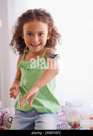 Wer sagt, dass kleine Mädchen Angst vor Spinnen haben? Porträt eines jungen Mädchens, das glücklich in ihrem Schlafzimmer spielt. Stockfoto