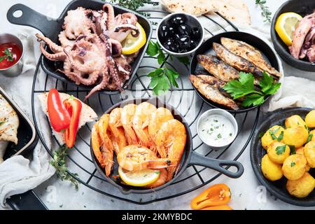Meeresfrüchte-Platte. Gemischte köstliche Meeresfrüchte mit Gemüse auf grauem Hintergrund. Draufsicht. Stockfoto