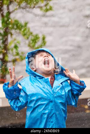 Freiheit im Regen. Ein junges Mädchen, das draußen im Regen spielt. Stockfoto