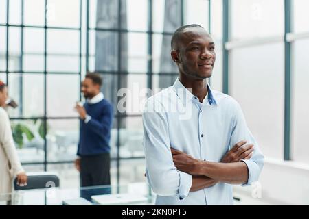 Junger Geschäftsmann, der im Büro steht. Stockfoto