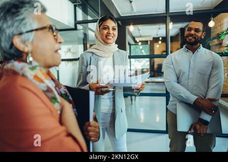 Multikulturelle Geschäftsleute, die eine Mitarbeiterversammlung in einem modernen Büro abhalten. Eine Gruppe von Unternehmern mit vielfältigen Geschäftsbereichen, die ein erfolgreiches Start-up in einer integrativen Stockfoto