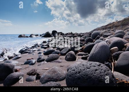 Schwarze Vulkansteine am Strand von Santorin Stockfoto