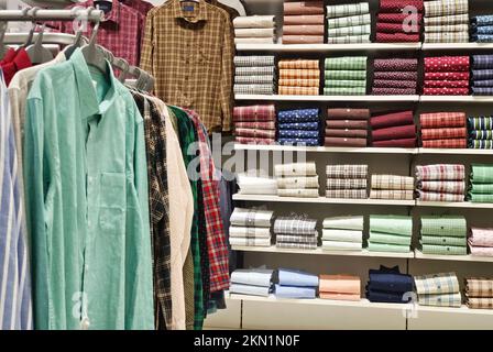 Das neueste indische Kleidungsstück für Männer hängt an Kleiderbügeln, in einem Laden auf dem Markt, traditionelle Kleidung für Männer. Stockfoto