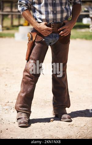 Du willst nicht auf seine schlechte Seite. Ein Cowboy mit der Hand in der Nähe seiner Waffe. Stockfoto