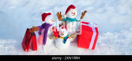 Weihnachtsbanner mit Schneemann. Glücklicher Schneemann mit Geschenk im Winter, schneebedeckt. Winterferien, Verkaufsbanner. Süßer Schneemann mit Hut und Schal Stockfoto