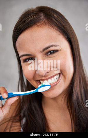 Mundgeruch wegbürsten. Ein isoliertes Porträt einer jungen Frau, die sich die Zähne putzt. Stockfoto