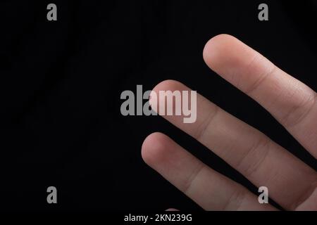 Drei Finger einer Hand des Kindes teilweise in schwarzen Hintergrund gesehen Stockfoto