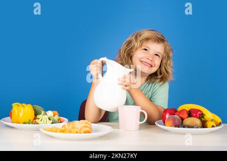 Das Kind schenkt Milch ein. Gesundes Kind gießt Milch aus dem Krug Stockfoto