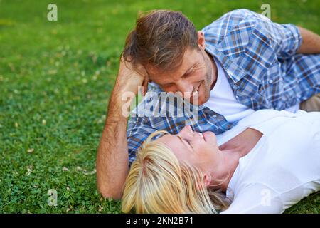 Ich könnte ihr für immer in die Augen sehen. Ein Paar, das auf dem Gras liegt. Stockfoto
