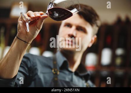 Bokal von Rotwein auf dem Hintergrund, männliche Sommelier schätzen Getränk Stockfoto