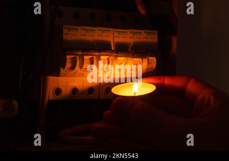 Blackout-Konzept. Die Hand einer Person in völliger Dunkelheit hält eine Taschenlampe in der Hand, um einen Sicherungskasten im Haus während eines Stromausfalls zu untersuchen. Stockfoto