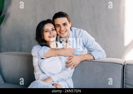 Liebevoller Ehemann Trost verärgerte Frau, liebte und umarmte sie von hinten. Ein fürsorglicher Mann, der Frieden schließt und sich mit seinem Geliebten versöhnt, sich wohlfühlt Stockfoto