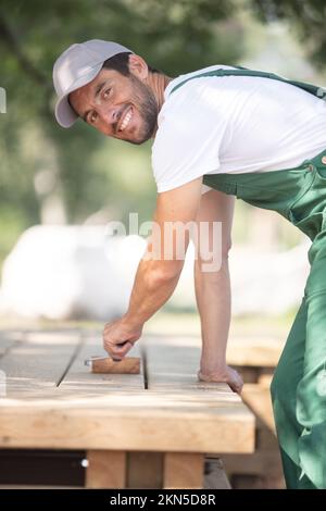 Ein Mann malt mit weißer Farbe auf Holzplanken Stockfoto