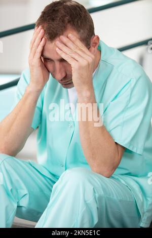 Männliche Krankenschwester gestresst im Krankenhaus Stockfoto