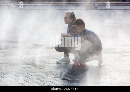 Zwei Kinder, ein Junge und ein Mädchen, posieren für einen Fotografen im Nebel am Place Rogier in Brüssel. Stockfoto