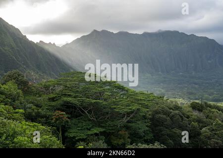 Der letzte Sonnenstrahl des Tages auf Ohau Hawaii, mit Blick auf ein wunderschönes grünes Tal und die Berge vor dem botanischen Garten Hoß omaluhia Stockfoto