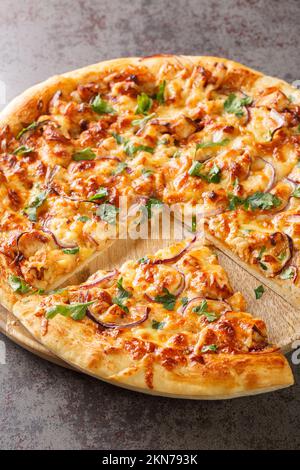 Hausgemachte Grillhähnchen-Pizza mit Zwiebeln und spezieller Sauce auf dem Holzbrett auf dem Tisch. Vertikal Stockfoto