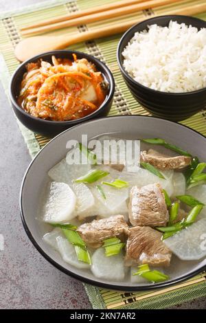 Soegogi muguk Beef and Radieschen Suppe ist eine sehr beliebte Suppe in Korea, serviert mit Reis und Kimchi Nahaufnahme auf der Matte auf dem Tisch. Vertikal Stockfoto