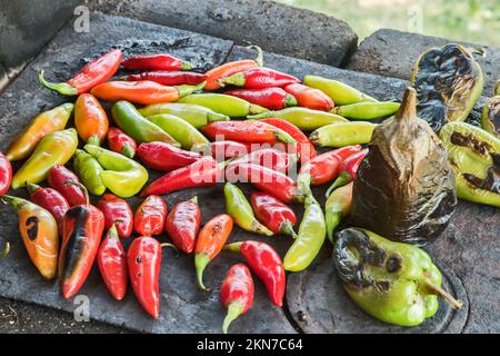 Paprika und Aubergine auf Eisenplatte auf rustikalem Herd im Freien rösten Stockfoto