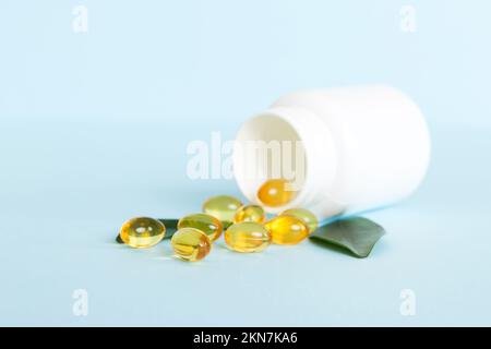 Weiche Geltabletten mit Omega-3-Öl, das aus der Pillenflasche aus der Nähe verschüttet wird. Gelkapseln Flasche weiße Oberfläche. Omega 3, Multivitamine, Kalzium, Antibiotika Stockfoto