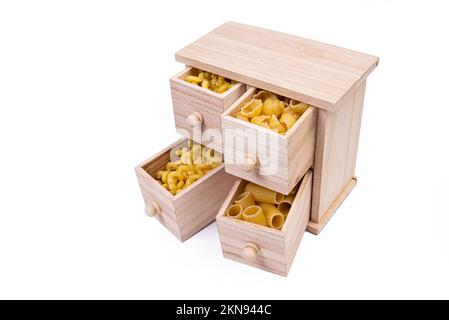 Verschiedene Arten italienischer ungekochter Pasta in Holzkiste, Vollkornpasta, Pasta, Spaghetti, Nudeln, Tagliatelle. Draufsicht, isoliert auf weiß Stockfoto