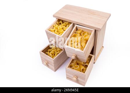 Verschiedene Arten italienischer ungekochter Pasta in Holzkiste, Vollkornpasta, Pasta, Spaghetti, Nudeln, Tagliatelle. Draufsicht, isoliert auf weiß Stockfoto