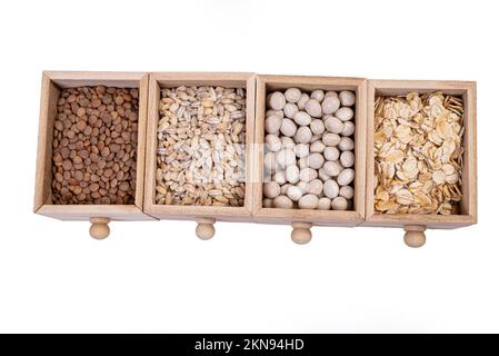 Muster von rohem Getreide, Bohnen und Samen, Oberflächenstruktur, Mischung aus Grobgrieß in quadratischer Holzbox. Kleine Holzbox mit Zellen mit Bohnen, Linsen, Haferbrei Stockfoto