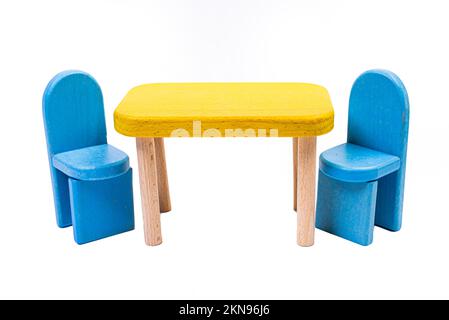 Ein blauer Spielzeugstuhl aus Holz, ein Sofa, zwei Stühle mit einem Tisch, ein gelber Tisch, blaue gepolsterte Holzstühle. Gelbe Lampe auf isoliertem weißem Hintergrund für Stockfoto