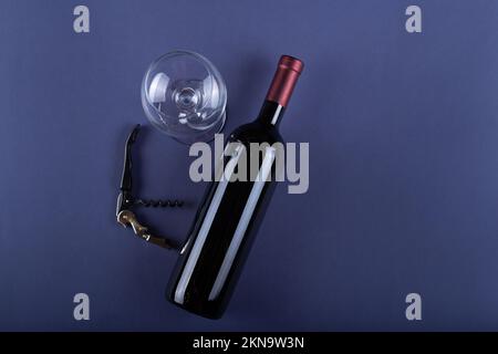 Rotwein-Flasche ohne Etikett, Korkenzieher und leeres Glas auf purpurem Papierhintergrund. Mockup Drink mit Platz für Sie Etikett und Text. Platz für Text. Stockfoto